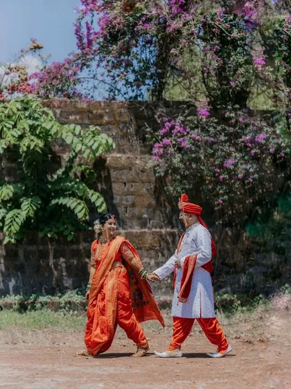 A candid shot of the couple walking hand-in-hand after their ceremony, framed by beautiful bougainvillea flowers.