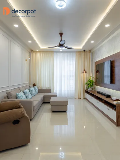 A perfect example of Scandinavian-inspired design, this living room uses a neutral color palette, a comfortable sectional sofa, and clean lines to create a calm and inviting space. The simple TV unit and wall molding add a touch of understated elegance.