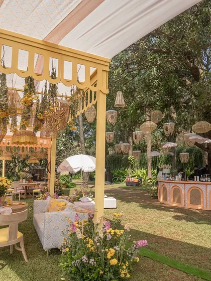 This riverside brunch in Goa captures a laid-back, bohemian luxury with pastel tones, lush florals, and natural textures like cane and wicker.
