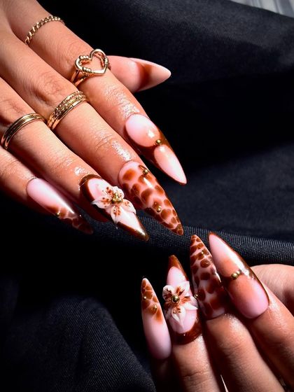 A beautiful set of stiletto nails featuring a giraffe print, ombre effect, and delicate 3D flowers.