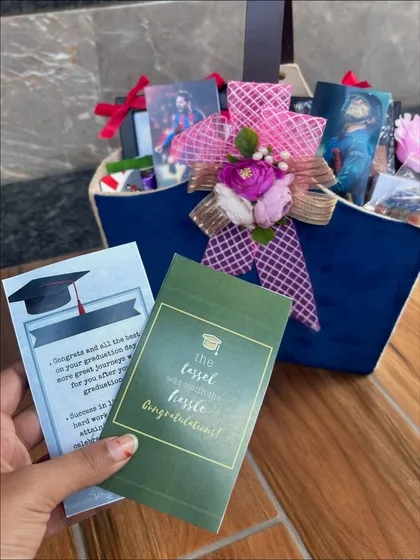 Holding up the personalized congratulatory cards from the graduation hamper. Every detail is designed to make the recipient feel celebrated for their hard work.