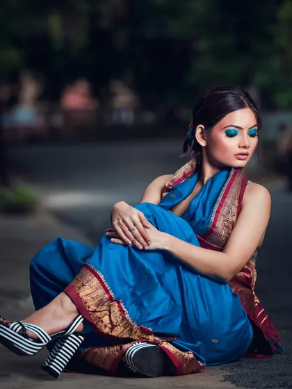 An urban-ethnic fusion shoot, pairing a traditional saree with modern platform heels. The street setting and bold blue makeup create a unique and contemporary fashion statement.