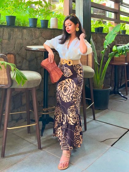 A summer outfit with an 'old money' aesthetic. I've paired a printed linen fishtail skirt with a classic white shirt, a jute belt, and a leather purse for a look that's perfect for a vacation or a weekend brunch.