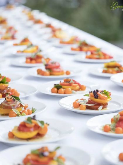 A long table set with dozens of individually plated appetizers, ready for a large event. This style of pre plated service is an elegant alternative to a traditional buffet, ensuring consistency and beautiful presentation.