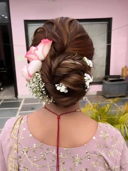A gorgeous messy bun adorned with pink-tipped roses and baby's breath. The combination of flowers adds so much texture and romance to this updo.