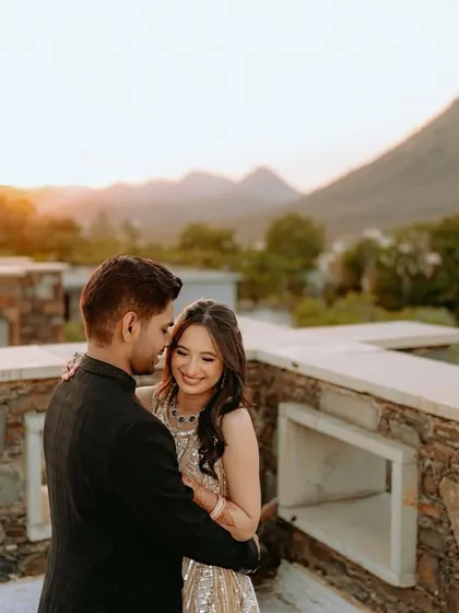 A romantic embrace on a stone terrace, with the mountains of Udaipur creating a serene and majestic background.