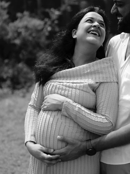 A black and white close-up filled with laughter and joy. His arm is around her, and they are both looking up, sharing a genuinely happy moment.