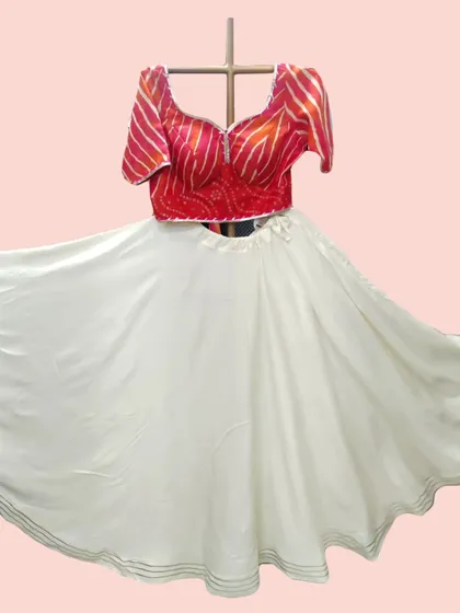 The pure white skirt of this lehenga creates a beautiful contrast with the vibrant red bandhani-style blouse, shown here in full flare.