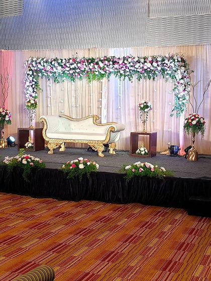 This image shows the balanced and symmetrical setup of a floral arch stage. The clean lines and classic floral arrangements make it a versatile choice for many indoor wedding venues.