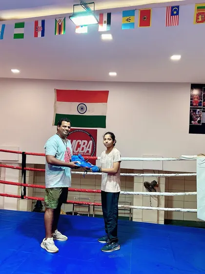 A wide shot of the coach gifting shoes to a student in the ring, a tradition at our academy.