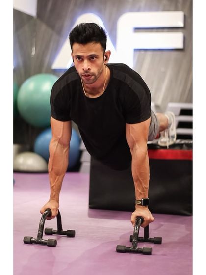 A trainer demonstrates perfect push-up form using parallettes, which allow for a deeper range of motion and reduced wrist strain.