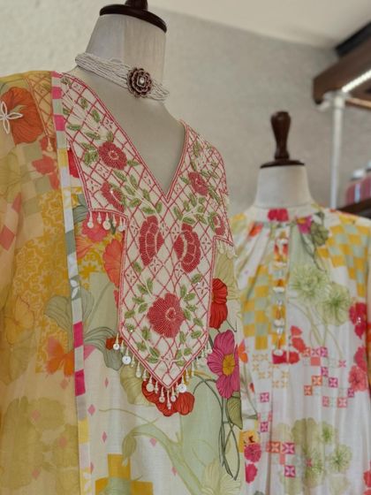 A detailed view of the intricate floral embroidery and tassel details on the neckline of a festive kurta.