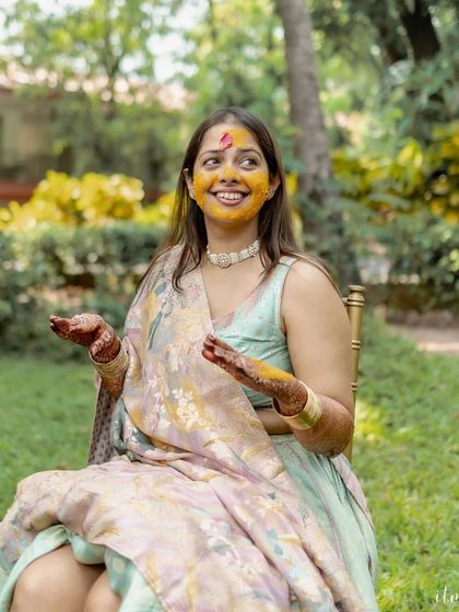 The bride's face covered in turmeric during a joyful Haldi ceremony. Her happy expression shows the fun and playful nature of this pre-wedding ritual.