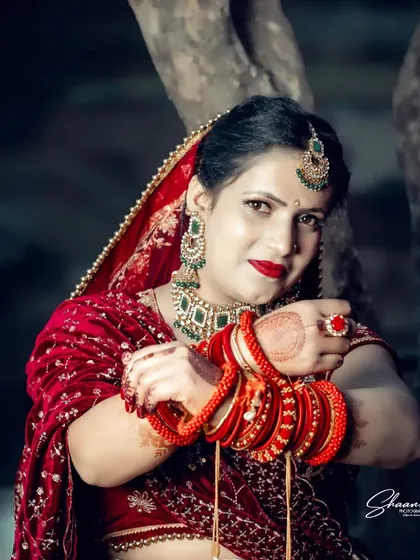 The vibrant red of a bridal lehenga stands out in this outdoor portrait. I focus on capturing the bride's confidence and grace, using lighting that makes the rich colors and intricate details of her wedding attire pop.