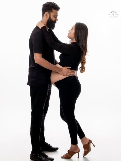 An intimate couple's portrait in matching black outfits against a white background, creating a timeless and classic look.