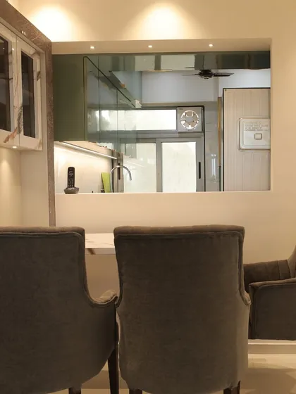 This dining area is connected to the kitchen through a serving window, which is a great way to link the two spaces. The comfortable, high-back chairs make it an inviting spot for meals.