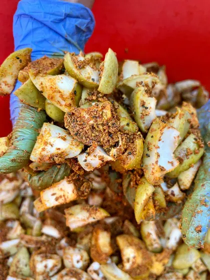 Mixing the masala into the raw mangoes by hand. This is a labour of love, ensuring every piece is perfectly coated with our special spice blend.