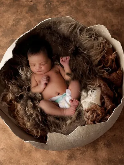 A truly unique concept of a newborn "hatching" from an eggshell. This artistic portrait uses creative props and textures to symbolize new life in a memorable and imaginative way.