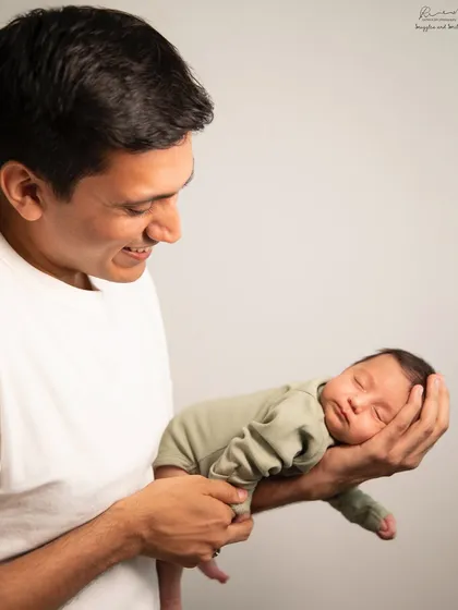 A father's hands are the perfect scale to show how tiny a newborn is. This sleeping baby fits so perfectly, showcasing the gentle strength and love of a new dad.