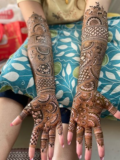 Two full arms covered in different but complementary designs, showing versatility in creating complex, full-coverage mehandi.