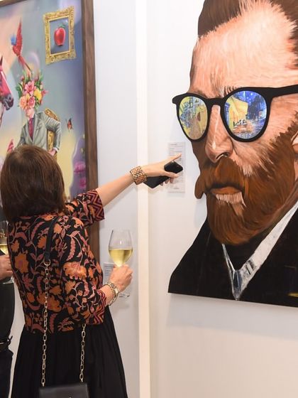 A guest uses their phone to scan a QR code next to a lenticular portrait of Van Gogh. This demonstrates our integration of interactive technology to provide deeper artist and artwork information during our events.