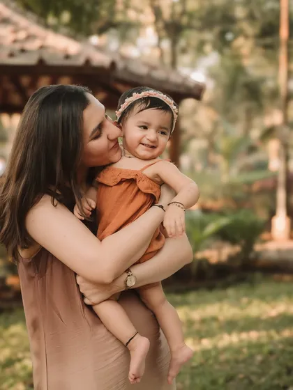 A mother's sweet kiss for her daughter during their outdoor family photoshoot.