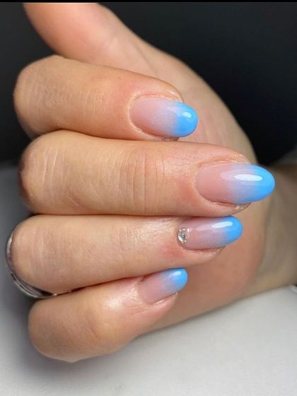 A cool and refreshing blue ombré effect. The color gradually fades from a sheer nude to a bright sky blue at the tips, accented with a single tiny rhinestone.