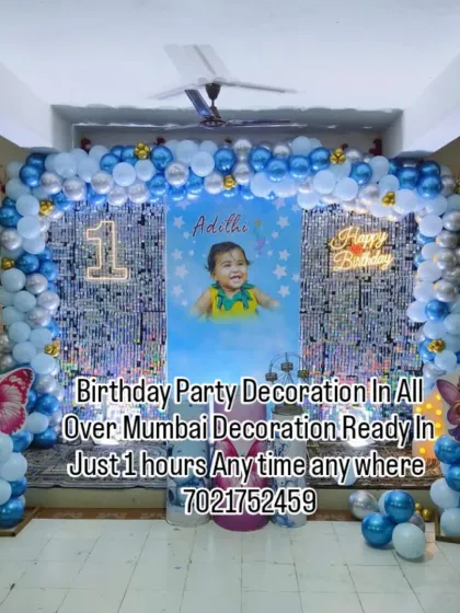 Make your child's first birthday extra special with a personalized photo backdrop. This blue and silver balloon arch frames a large poster of the birthday baby, creating a beautiful memory.