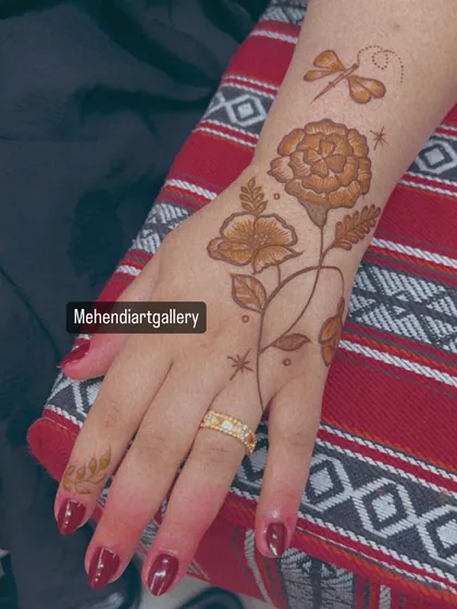 The full view of the dragonfly and floral mehendi on the back of the hand. The placement creates a beautiful, flowing composition.