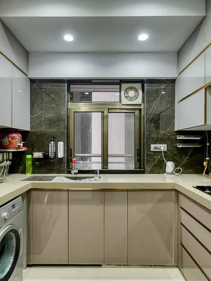 An elegant C-shaped acrylic kitchen with gold-toned profiles. The design includes integrated appliances and a washing machine, showcasing our ability to create highly functional and customized layouts.
