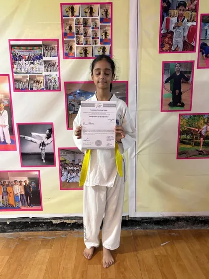 With a smile of accomplishment, this student displays her certificate for advancing to the next taekwondo grade. Each certificate is a testament to her dedication and hard work.