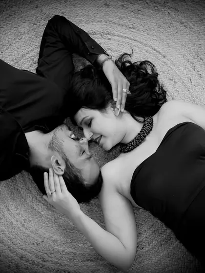 An artistic black and white overhead shot. This couple shares an intimate moment lying on a textured rug, creating a unique and romantic perspective.