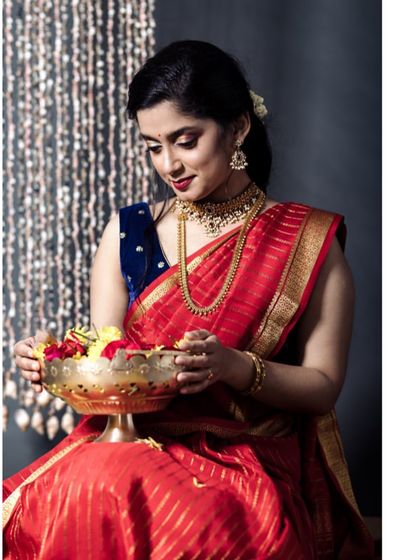 A graceful portrait of the model holding a brass bowl of flowers. Her elegant posture and the traditional elements make this a beautiful representation of festive celebrations.