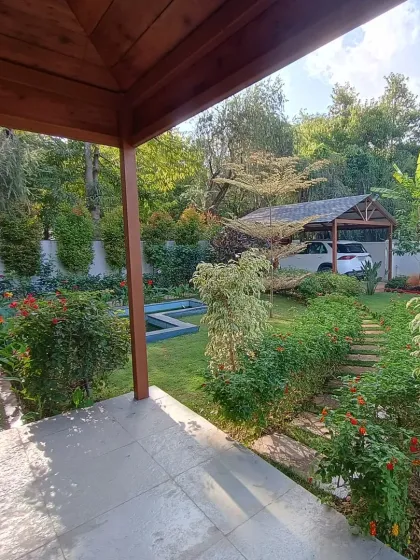 This view from the covered patio shows the different zones of the garden, including a stone pathway, a small pond, and lush planting beds with a mix of flowering shrubs.