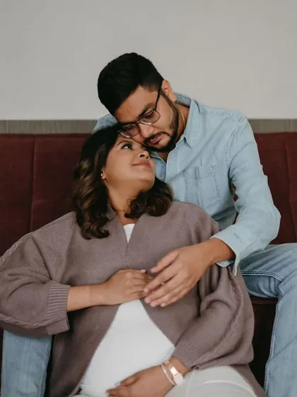 An intimate and cozy indoor shot from their maternity session. The makeup is soft and warm, creating a comfortable and loving atmosphere.