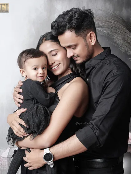 A loving family embraces, dressed in elegant black. This intimate portrait captures the warmth and closeness between parents and their child.