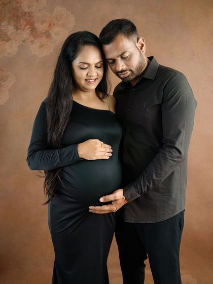 An elegant and moody portrait of a couple in matching black outfits, sharing a quiet and intimate moment.