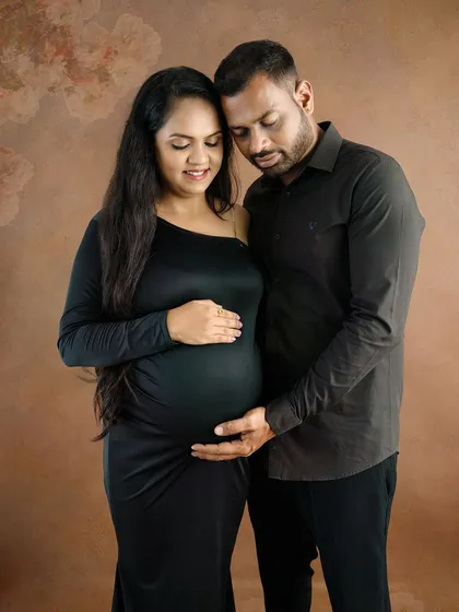 An elegant and moody portrait of a couple in matching black outfits, sharing a quiet and intimate moment.