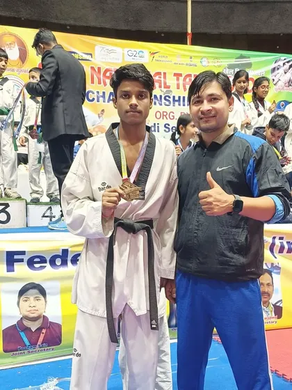 A student with his bronze medal, standing proudly on the podium.