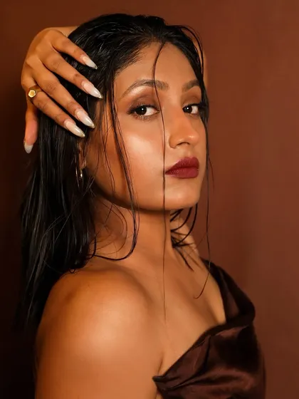 A close-up of the sultry, wet-look makeup. The glossy skin and hair, paired with a deep berry lip, create a high-fashion, edgy vibe.