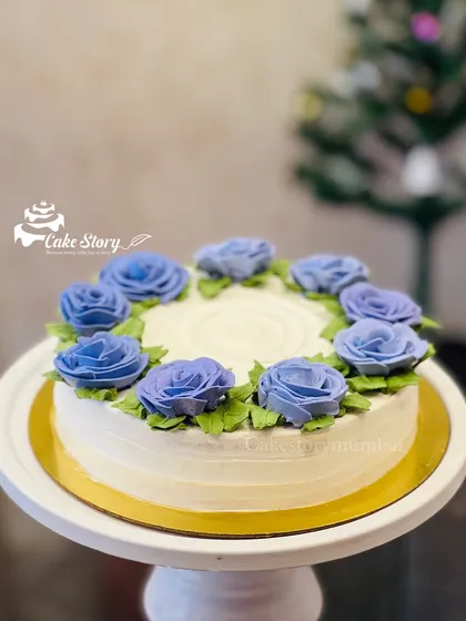 A simple and elegant floral cake. The white cake is adorned with a ring of beautiful, hand-piped purple roses.
