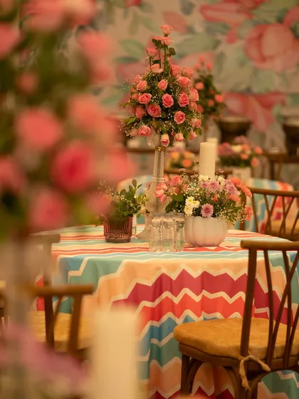 A beautiful table setting with a vibrant chevron-patterned tablecloth and a centerpiece of pink roses. The mix of bold patterns and soft florals creates a playful yet elegant look.