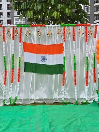 An outdoor decoration for Independence Day celebrations in a society, featuring a photo booth with the Indian flag and tricolor balloon pillars.