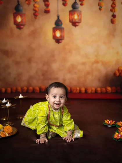 A wide shot capturing the baby crawling amidst the beautiful Diwali decor, with diyas and marigolds creating a warm atmosphere.