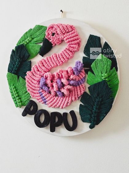 This custom nameplate was a special request to create a swan instead of a flamingo, using a unique pink and purple color scheme. I loved the challenge of bringing this vision to life with detailed macramé knots and lush green leaves.