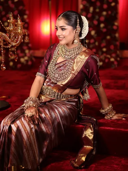 A happy, smiling South Indian bride, her joy lighting up the room as much as her golden jewellery.