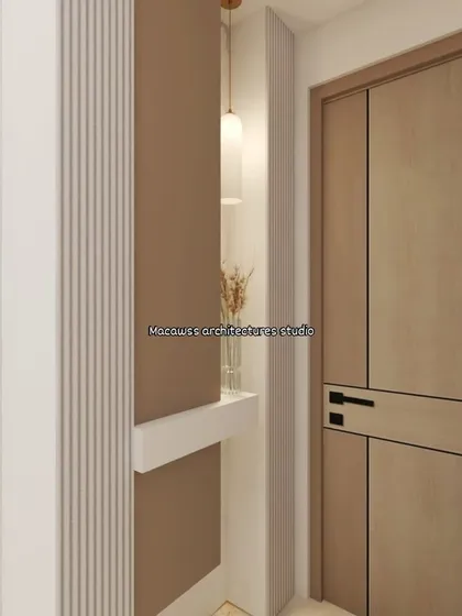 A close-up of an entryway detail, showing the interplay of textures with fluted paneling, smooth walls, and a modern wooden door. A small niche with a pendant light adds a decorative touch.