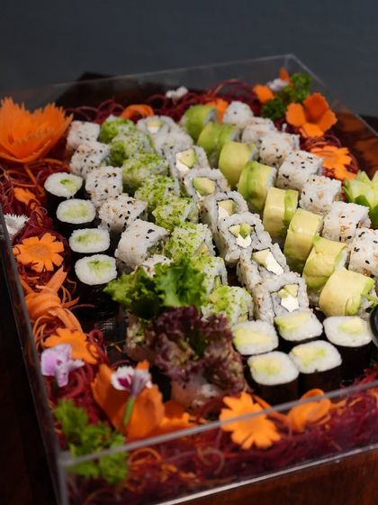 A closer look at our vegetarian sushi party platter. It includes a variety of rolls like avocado maki, cucumber maki, and other vegetable-filled rolls, all artfully arranged on a bed of shredded carrots and microgreens.