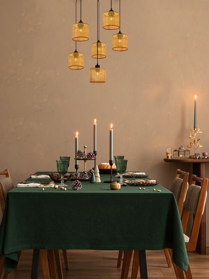 A cluster of woven amber pendants hangs over a festive dining table, creating a warm and intimate atmosphere. The lighting is perfect for making holiday celebrations shine brighter with elegance.