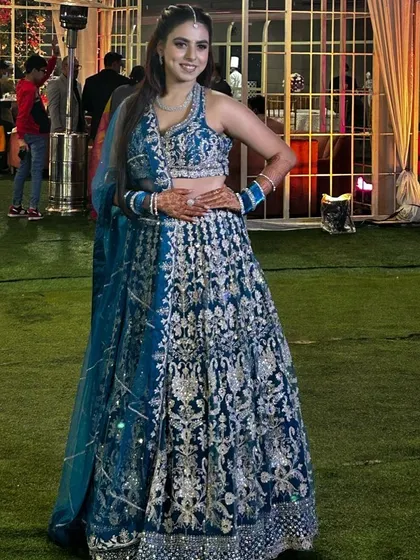A happy client looking radiant in a peacock blue lehenga with dense silver embroidery. This is a popular rental for its rich color and festive look, perfect for a wedding guest or bridesmaid.